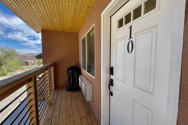 Garage with mountain bikes on rack, climbing gear on walls, and desert rock formations visible through open door