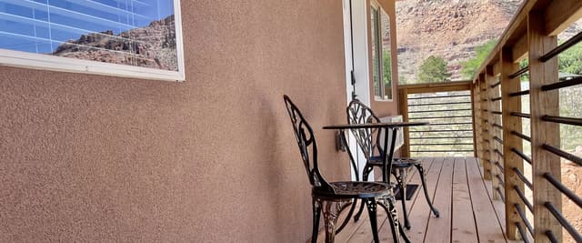 Covered deck with metal chairs, wooden railings, and mountain views through large windows
